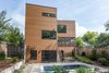 Modern home with Exterior, House Building Type, Flat RoofLine, Metal Siding Material, Metal Roof Material, and Wood Siding Material. The rear elevation facing the pool area. Cedar fencing traces the property lines on both sides. Photo 7 of The Thomas Residence