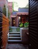 At the threshold between the public realm and the private. This image is taken at the point of entry to the garden, adjacent the garden shed and driveway that it conceals. In view are the brick pavers, cedar fence, bluestone treads, board form concrete water feature, and the new kitchen addition with roofdeck beyond. By RobitailleCurtis Photo 3 of Fitler Square House & Garden modern home