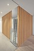 Modern home with Hallway, Medium Hardwood Floor, and Concrete Floor. The atrium is 'enclosed' at the second floor level by vertical grain douglas fir slats. The trapeze net play surface on the third floor can be seen. Photo 8 of Atrium Townhome