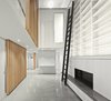 Modern home with Living Room, Gas Burning Fireplace, Ceiling Lighting, Bookcase, Shelves, Accent Lighting, Concrete Floor, Recessed Lighting, and Standard Layout Fireplace. The Atrium Townhome by Robitaille Curtis has a 32-foot atrium with a skylight running the full width of the house. The third story features a net “floor” at the top of the atrium that turns the void into a dramatic play surface adjacent to the kid’s bedrooms. The use of a net in this location precludes the need for guardrails and opens the floor plan to unimpeded views to and from the third floor. Riggers from Cirque du Soleil provided and installed the trapeze net. Photo 2 of Atrium Townhome