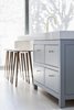 Modern home with Kitchen, Colorful Cabinet, Marble Counter, and Light Hardwood Floor. Close-up view of custom kitchen island designed by RobitailleCurtis, built by Kastella. Solid wood C401 stool by Kastella in rustic walnut with oil rubbed finish. Island has a 4" Carrara marble counter. Floors are ash with a custom white tint applied on site. Photo 8 of Hampstead House