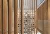 View through the atrium and custom designed Douglas Fir wood screen to the custom bookcase and library ladder. The net play surface at the third-floor level is above. Photo of Atrium Townhome modern home