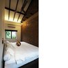 The masterbed room with crisp white linen, a copper bedside lamp from America and more exposed brickwork that flows from the dining and living areas. The wooden ceiling fan was hand-carried from Bangkok, Thailand. Photo 11 of The Singapore Designer Loft: A Fusion of Old and New modern home
