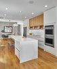Modern home with Kitchen, Refrigerator, Wall Oven, Stone Counter, Wood Cabinet, Light Hardwood Floor, Stone Slab Backsplashe, Recessed Lighting, White Cabinet, Pendant Lighting, and Undermount Sink. Kitchen Photo 14 of The Historic Ely Building