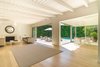 An open, light-filled living room with a fireplace and exposed beams is designed for embracing the quintessential California lifestyle, with sliding walls of glass to a fully-hedged swimming pool. Photo 2 of Nichols Canyon modern home