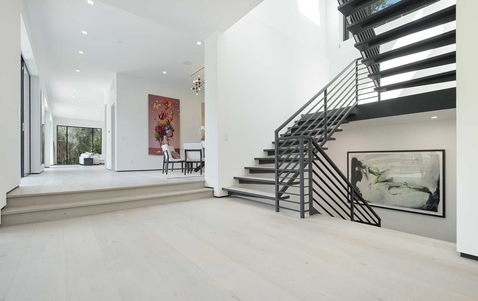 An airy foyer and light-filled corridor with sliding walls of glass and high ceilings that enhance the space and scale of every room.