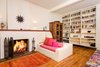 Modern home with Living Room, Bench, Wall Lighting, Sofa, Medium Hardwood Floor, and Wood Burning Fireplace. The home's original period details, which include reclaimed wood beams, built-in bookshelves and seating nooks and a wood-burning fireplace, imbue the home with a sense of history and whimsy. Photo 3 of A Charming 1920s Spanish in West Hollywood's Storied Norma Triangle