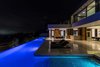 Ideal for entertaining, the home's expansive terrace boasts striking fire features, dining and lounge areas, and a distinctive, crescent-shaped 110-foot long infinity pool that appears to spill over the hillside. Photo 2 of A Showpiece on Shadow Hill modern home