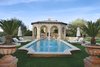 Designed by Santa Barbara landscape architect Puck Erickson, the grounds offer a glimpse into a timeless paradise. Spectacular archways line the grand sitting area, which features an outdoor fireplace, rose garden, and built-in barbecue, while the mosaic tiled pool's dazzling waters lead up to a poolside cabana with a wet bar and picturesque views of Pinnacle Peak. Photo 10 of A Wallace Neff Inspired Masterpiece in Desert Highlands modern home