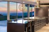 Modern home with Kitchen, Light Hardwood Floor, Range Hood, Ceiling Lighting, Wood Cabinet, and Accent Lighting. The custom-fabricated, Italian Del Tongo chef’s kitchen looks onto the sweeping cityscape. Photo 6 of An Architectural Gem on the Bird Streets of Los Angeles