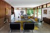 Modern home with Living Room, Coffee Tables, Concrete Floor, Wood Burning Fireplace, Recessed Lighting, Track Lighting, Console Tables, Sectional, End Tables, Rug Floor, Pendant Lighting, Chair, and Table. The front great room is intentionally public; the furniture-like wall (inspired by Mies’ Farnsworth house) creates privacy for all other rooms—even with no window coverings. No rooms have interior walls that connect with the outer perimeter of the house, echoing a design element of our 1958 E. Stewart Williams house in Palm Springs, CA. Photo 5 of Pleasant Street Residence