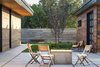 Modern home with Outdoor, Front Yard, Side Yard, Trees, Shrubs, Gardens, Hardscapes, Walkways, Flowers, Grass, Large Patio, Porch, Deck, Concrete Patio, Porch, Deck, Pavers Patio, Porch, Deck, Planters Patio, Porch, Deck, Concrete Fences, Wall, and Horizontal Fences, Wall. A rough board-formed concrete wall hems in the courtyard garden creating an organic looking transition to the wild scrub oak beyond. Photo 16 of Red Hawk