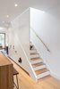 Modern home with Kitchen, Refrigerator, Wood Counter, Marble Counter, White Cabinet, and Light Hardwood Floor. Cabinetry under stairs containing fridge, pantry, and porthole entry to cat litter box Photo 3 of Ritchie Rowhouse
