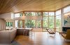 Modern home with Kitchen, Ceiling Lighting, Cooktops, Wood Cabinet, Engineered Quartz Counter, Medium Hardwood Floor, Refrigerator, Undermount Sink, Recessed Lighting, and Wood Backsplashe. Each layer of Gregory Creek Residence relates differently to the surrounding natural environment. “Overall an open visual flow connects those in the home to the creek and its creatures, while offering protection via the use of cantilevers,” says Gettliffe Architecture. Photo 6 of Gregory Creek Residence