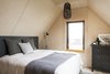 Modern home with Bedroom, Bed, Dresser, Light Hardwood Floor, Floor Lighting, Pendant Lighting, and Rug Floor. Branchless plywood was used to create rustic planking for the interior walls and floors. An earthy and warm color scheme combined with sparse Scandinavian decor brings a touch of old world charm into this cozy, modern coastal retreat. Photo 6 of Modern Coastal Barn