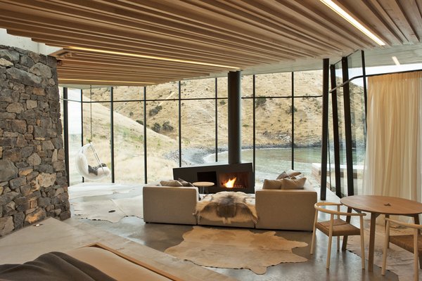 Designed by award-winning Auckland architect Andrew Patterson, this remote one-bedroom house, which rests on a rocky escarpment in a sheltered cove, is constructed as an angular, modern, stone-and-glass enclosure that looks out to breathtaking views of Pigeon Bay&mdash;a deserted, rocky bay where seals and dolphins often show up.