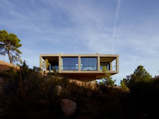 Set on the edge of Puertos de Beceite national park in Aragon, Spain, and available for vacation rentals, Casa Solo Pezo is a striking concrete square structure set on top of a smaller concrete square bass. Designed by award-winning and MoMA-exhibited Chilean architects at Pezo Von Ellrichshausen, this thoroughly modern residence has proportions and an interior layout that follows those of traditional Mediterranean homes with a strong indoor/outdoor connection. Its board-formed concrete exterior gives the building a texture and pattern that lend an almost organic, natural feel despite its very rectilinear form.