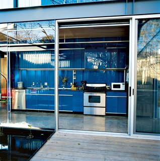 If you're a minimalist, you may prefer hingeless track doors over swinging doors with handles. In this steel-frame Texas home, the bright blue galley-style kitchen has no visible hinges, which makes it look like it's one with the similar-colored back wall.