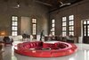 Modern home with Living Room, End Tables, Chair, Table, Storage, Wall Lighting, and Console Tables. The hotel’s bar, which is sited where the sugar press once stood, was given a 1960s industrial makeover by Horizontal Space Design and includes a red circular lounge that's sunken into the middle of the space. Photo 16 of Alila Yangshuo