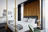 Modern home with Bedroom, Bed, Lamps, Chair, Table Lighting, Wall Lighting, Night Stands, and Dark Hardwood Floor. Wood, leather, marble, and dark, earthy colors are contrasted with glossy, polished-copper details to create a sensual European concept that’s jazzed up with contemporary, avant-garde elements. Photo 3 of Roomers Munich