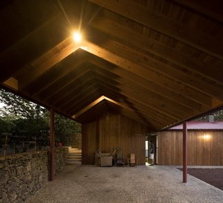 A wide, open-air, stone-paved corridor with a saltbox roof shelter.