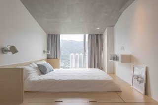 Fuss-free aesthetics continue into the master bedroom, where a sloped roof with concrete paint hides the ceiling beam.