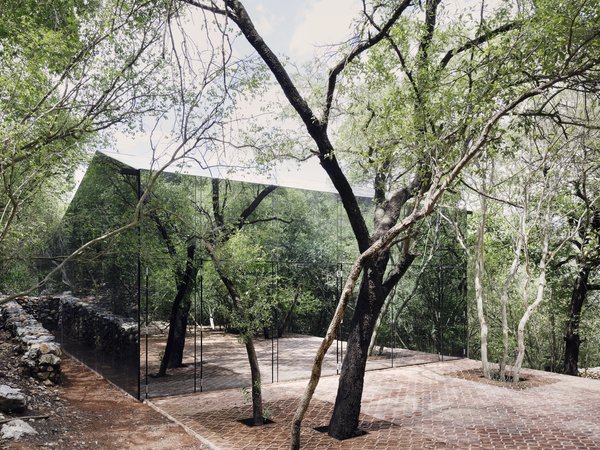 Named Los Terrenos, meaning The Terrains, this retreat in Monterrey, Mexico, was designed by Mexico City–based architect Tatiana Bilbao to reflect the lush woodland hillside it sits on. The dwelling consists of two volumes made of rammed earth, terracotta clay bricks, and a facade clad in mirrored glass.