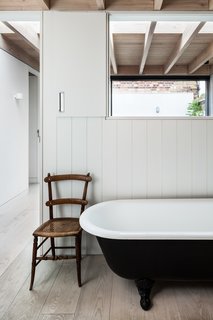 The main bathroom is located off the stairwell. This area has cut-out openings that draw in plenty of light from a courtyard garden sited on the opposite side of the open-tread stairs.

