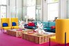 Modern home with Living Room, End Tables, Chair, Carpet Floor, Coffee Tables, Sofa, Table Lighting, and Wall Lighting. Geometric furniture combines with super-saturated colors, custom-made Acacia wood cocktail tables, a 14-foot-long sofa, modern yellow wingback chairs, and blue metal end tables to bring plenty of youthful dynamism to the space. Photo 6 of Shoreline Hotel Waikiki