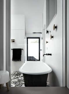 The only door in the addition is a repurposed stable door in the ensuite bathroom, which has a freestanding bathtub and monochromatic tiles. 

