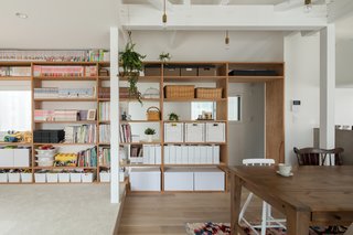 On the second level, part of a structural wall was removed and replaced with built-in plywood shelves to create a permeable partition that encourages visual connectivity between the dining area and the stairs.