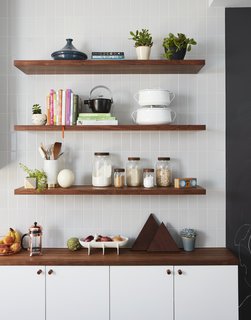 A mix of IKEA and custom walnut shelving; gray subway tile from Nemo Tile; and accessories from Food 52. 