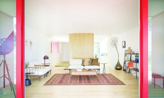 The entire exterior of the house is painted a bright, bold red, yet the interiors have been furnished with a calm, neutral palette—ones with lighter, more muted reds. 