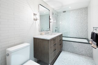 The first-floor bathroom is fitted with Carrara marble countertops, polished chrome Kohler fixtures, and a large Restoration Hardware vanity with cypress cabinetry.