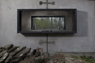 The concrete cabin has a steel chimney and steel window frames.