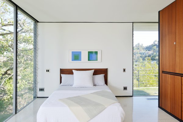 Fully glazed walls open the bedroom to the green outdoors.