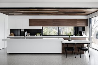 Spotted gum accents an otherwise white kitchen. The countertop drops down at one end to turn into a breakfast bar.