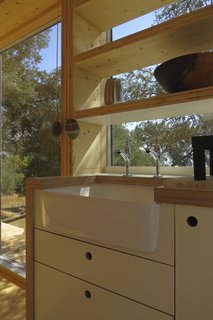 The kitchen unit hangs in front of the full height window, and is built in CLT faced in cool, white laminate with exposed edges.