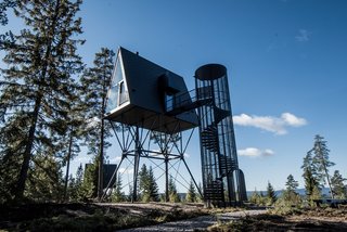 A spiral staircase, inspired by fire lookout towers, leads up to the A-frame cabin.