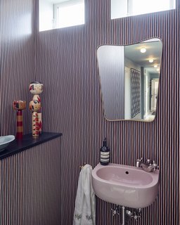 A brass mirror and Japanese Kokeshi dolls add whimsical, vintage touches in contrast to the wallpaper by Helene Blanche of Tapet Café.