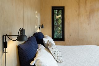 A slender window in the bedroom looks out to the trees.