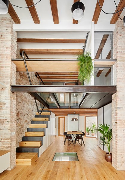 Built in the late 19th century as a storage warehouse for bananas, this stone building in Barcelona’s Sant Antoni neighborhood was partially destroyed by air raids during the Spanish Civil War. Despite the damage, local architect Valentí Albareda of Metric Integra saw potential in the building’s stone walls, handmade rasilla bricks, and vaulted basement. Albareda worked to transform the crumbling building into a 1,389-square-foot triplex residence.