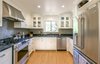 Modern home with Kitchen, Granite Counter, White Cabinet, Medium Hardwood Floor, Glass Tile Backsplashe, Ceiling Lighting, Recessed Lighting, Refrigerator, Cooktops, Range Hood, Dishwasher, Range, and Undermount Sink. White Farmhouse Kitchen Remodel Photo 2 of White Farmhouse Kitchen Remodel