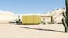 The desert loft resident is involved in off-road activities and required a place, which would sustain its appearance through sandstorms and extensive heat. The massive metal structure elegantly sits in the harsh environment.
The entrance door, secluded behind the thick metal screen, leads to the largest area of the house, unifying the kitchen, the dining room and the living room. The hall connects to three bedrooms and the bathroom.
The dining room exits to the terrace with the fireplace, carved in the floor. the ceiling is hollowed out right above it, following the lines of the round cut out in the floor. The gap's presence is almost poetic, as if it's the only passage transferring the smoke to the sky.
Photo 4 of Warmhole modern home