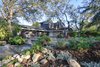 Modern home with Front Yard, Wood Fences, Wall, Horizontal Fences, Wall, Outdoor, Woodland, Garden, Rooftop, Slope, Vertical Fences, Wall, Trees, Shrubs, Hardscapes, Gardens, Boulders, and Walkways. After_ street view looking south east Photo 2 of Alpine Street