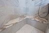 Book matched marble shower wall tiles and honed Calcutta marble seats to match the vanity countertops. Photo 7 of Modernized English Style modern home