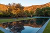 Infinity pool, green grass and tennis court in the backyard. Photo 4 of Malibu Lake House modern home