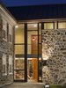 Modern home with Hardscapes, Stone Patio, Porch, Deck, Pavers Patio, Porch, Deck, Picture Window Type, Wood, Awning Window Type, Swing Door Type, Exterior, Front Yard, Small Patio, Porch, Deck, Landscape Lighting, Walkways, and Doors. The addition includes a redesigned entry sequence and acts as a threshold to an adjacent terrace and the site beyond. Photo 5 of Modern Farmhouse Addition