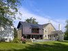 Modern home with Field, Back Yard, Vegetables, Hardscapes, Stone Patio, Porch, Deck, Grass, Trees, Large Patio, Porch, Deck, Pavers Patio, Porch, Deck, Outdoor, and Landscape Lighting. The addition's window wall and stone patio connect living spaces to the site beyond. Photo 2 of Modern Farmhouse Addition