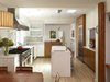 Modern home with Bench, Sofa, Chair, Bookcase, Pendant Lighting, Media Cabinet, Light Hardwood Floor, Kitchen, Engineered Quartz Counter, Wood Cabinet, White Cabinet, Mosaic Tile Backsplashe, Glass Tile Backsplashe, Refrigerator, Range, Range Hood, Wine Cooler, Dishwasher, Drop In Sink, and Undermount Sink. Ample floor-to-ceiling storage along the party wall minimizes wall cabinets and allows the narrow townhouse kitchen to feel airy and open. Photo 4 of Urban Garden House